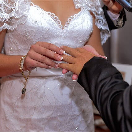 Une fiancée passe une bague de mariage au doigt du fiancé.