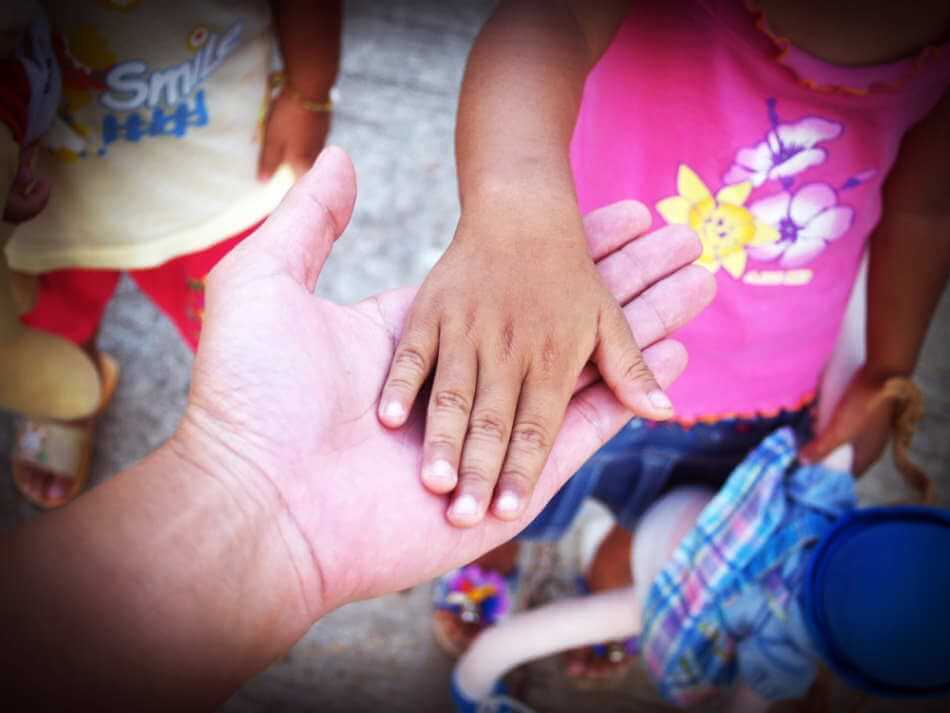 Un adulte donne la main à un enfant.