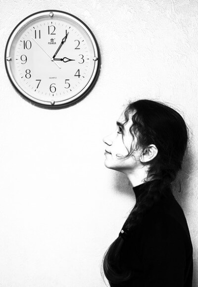 Une jeune femme immobile regarde une horloge.
