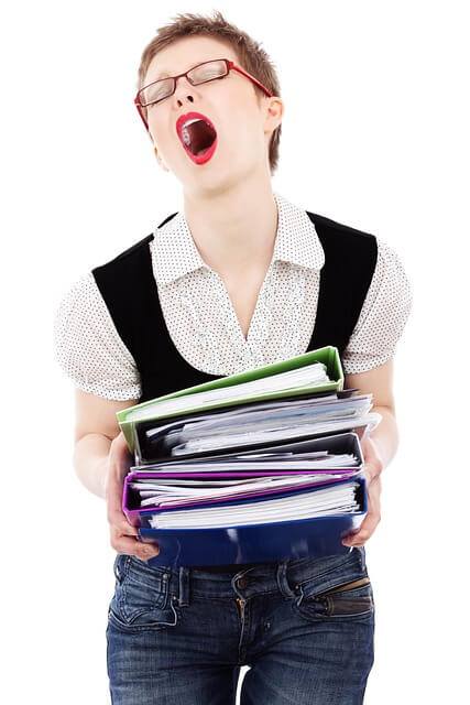 Une dame semble découragée par une grande pile de documents.