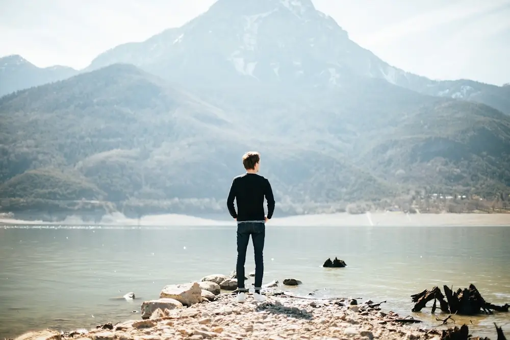 Un homme seul debout devants de magnifiques montagnes.