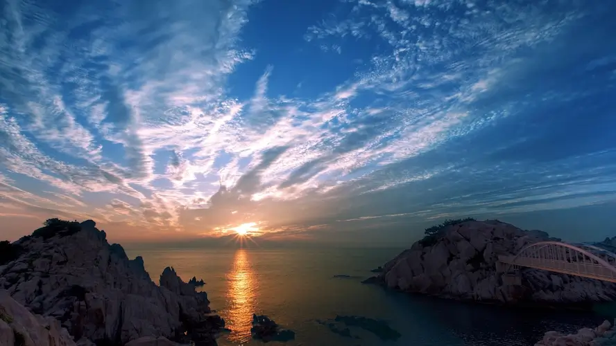  Un lever de soleil sur l’océan derrière des rochers.