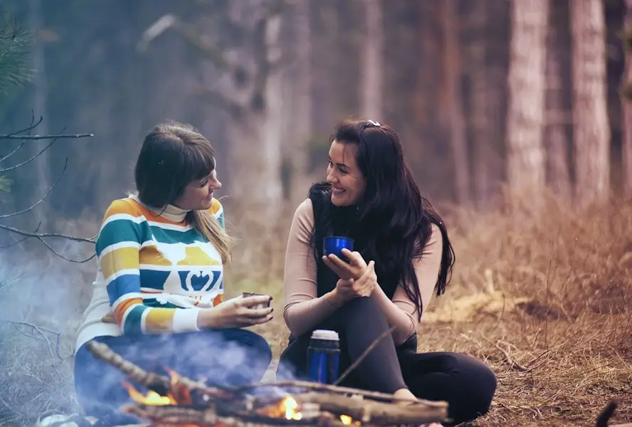 Deux amies parlent autour d'un feu de camp.