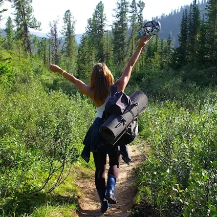 Une jeune femme marche dans un sentier forestier.