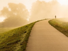 Une dame marche sur un sentier brumeux.